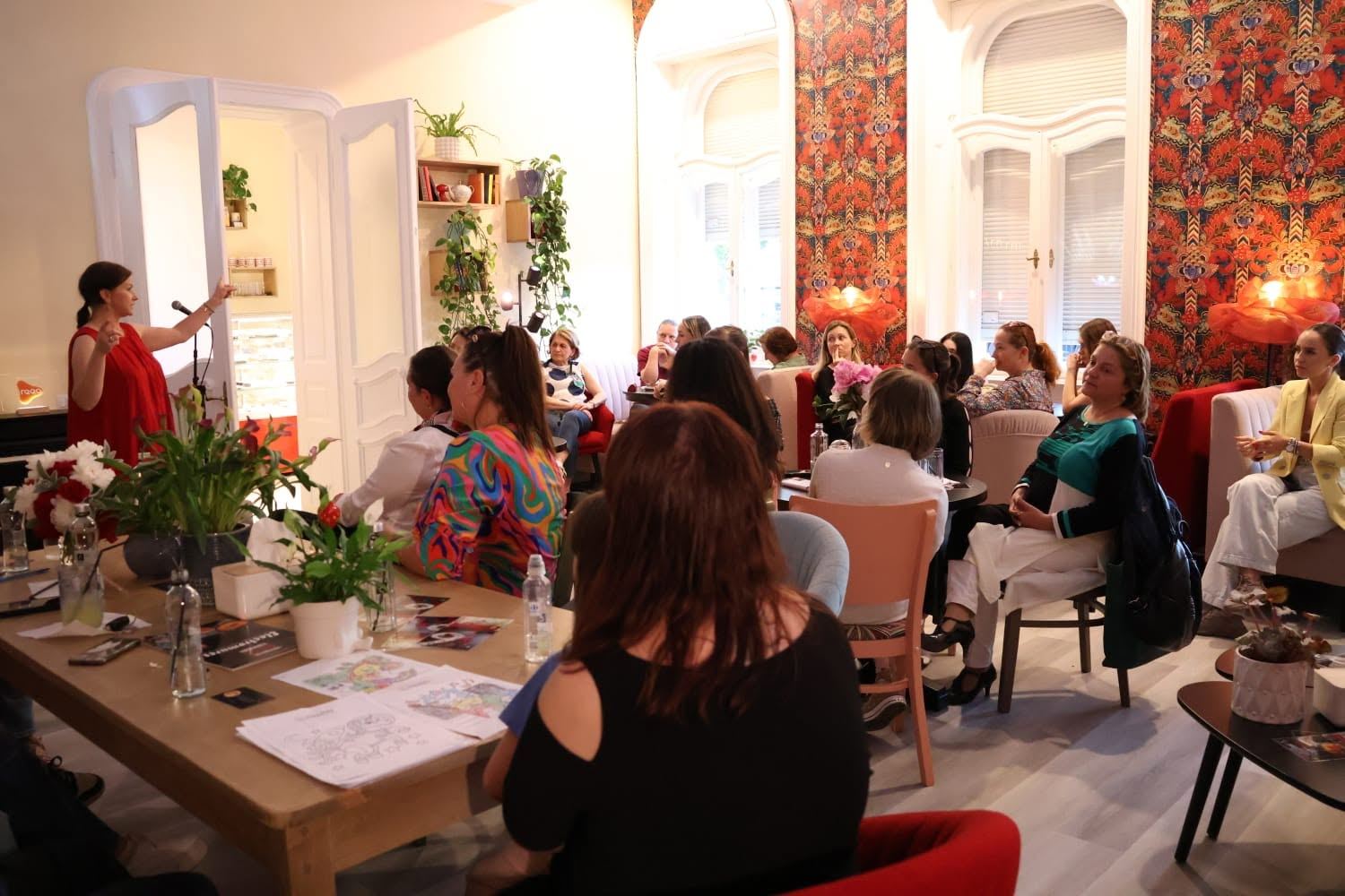 Prezentare în fața publicului în sala Artizan HUB, cu tapetul floral pe fundal