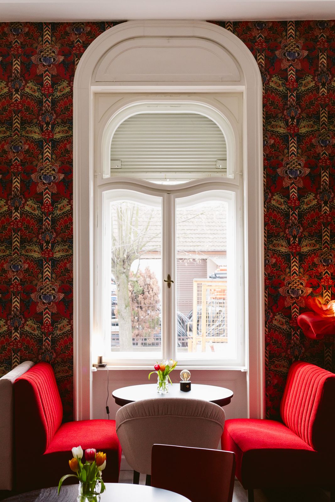 Colț din sala Artizan, fereastră arcuită, tapet floral și fotolii roșii